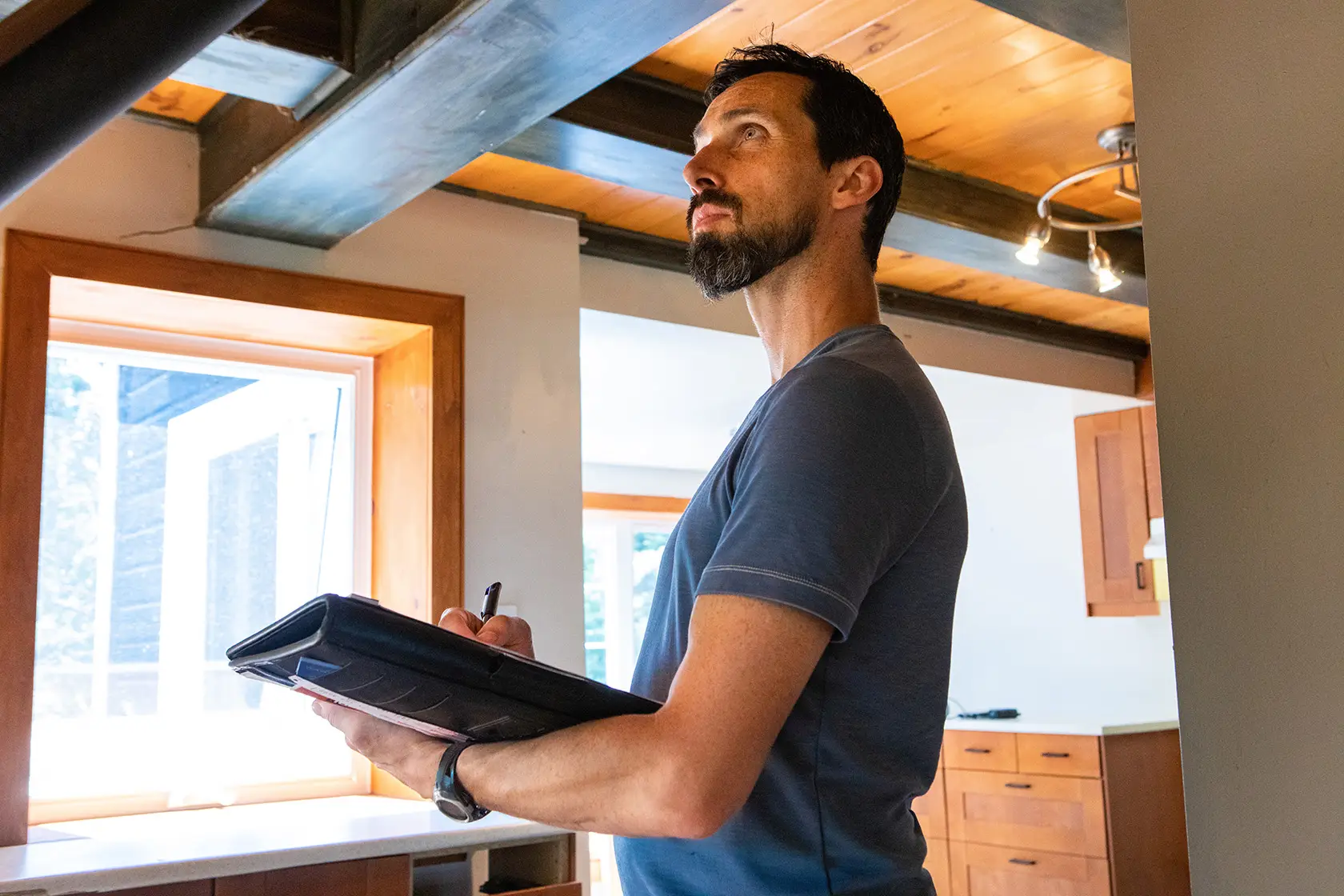 Male Home inspector looking around and taking notes on a clip board