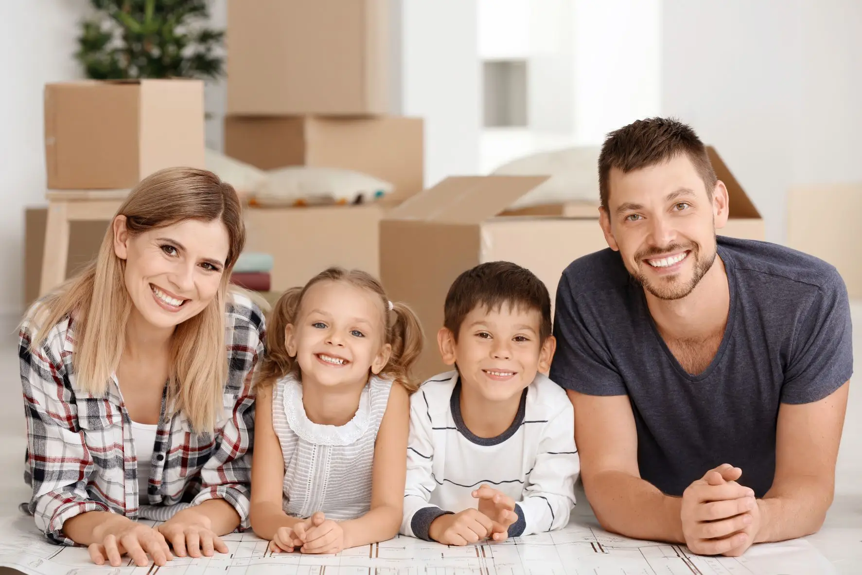 Young caucasian family of four surrounded by boxes